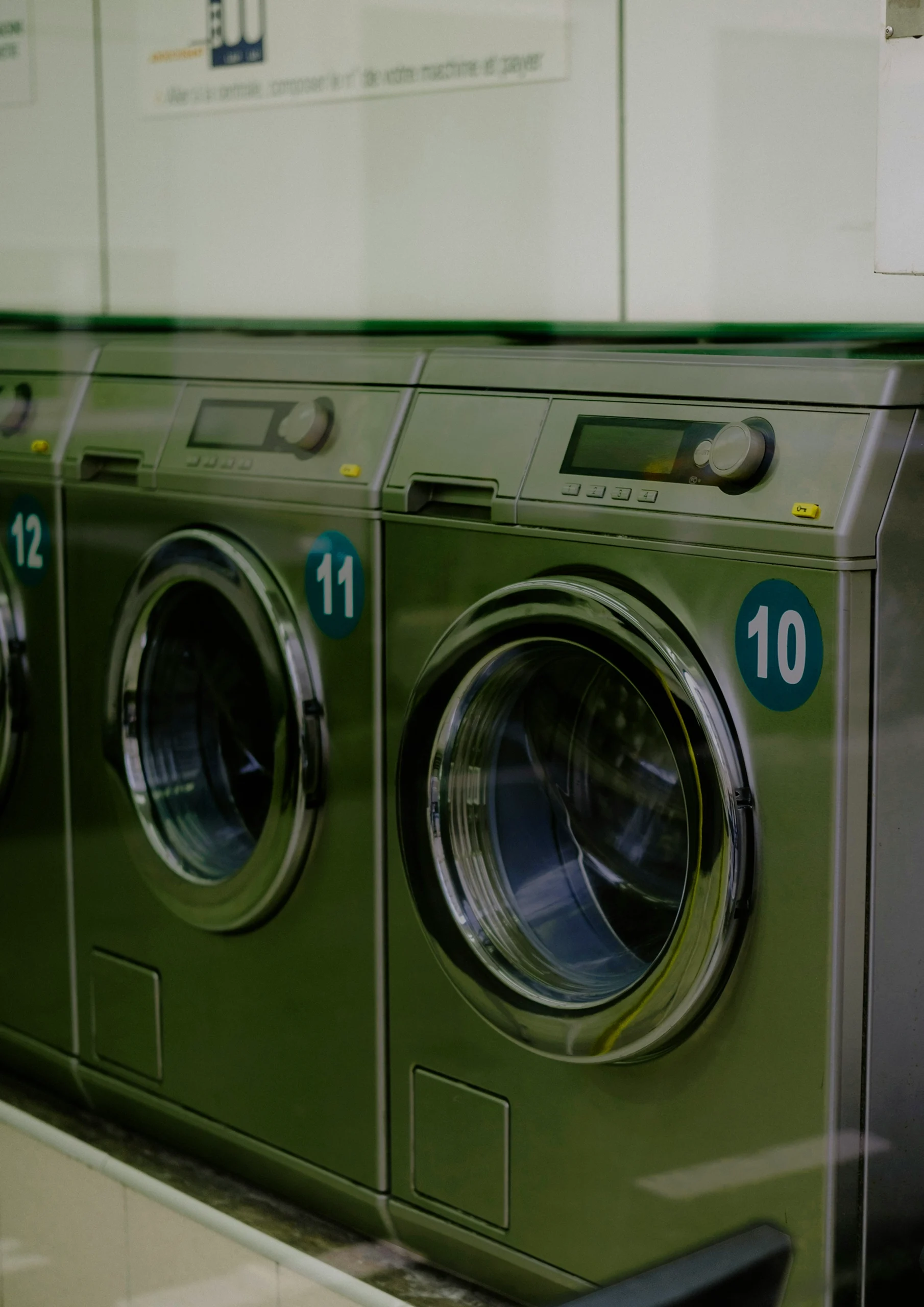 Polly Housekeeping professional in white shirt and signature green apron sorting and loading laundry into a washing machine